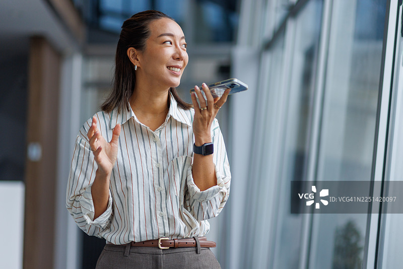 亚洲女商人正在办公室用智能手机录制语音消息图片素材