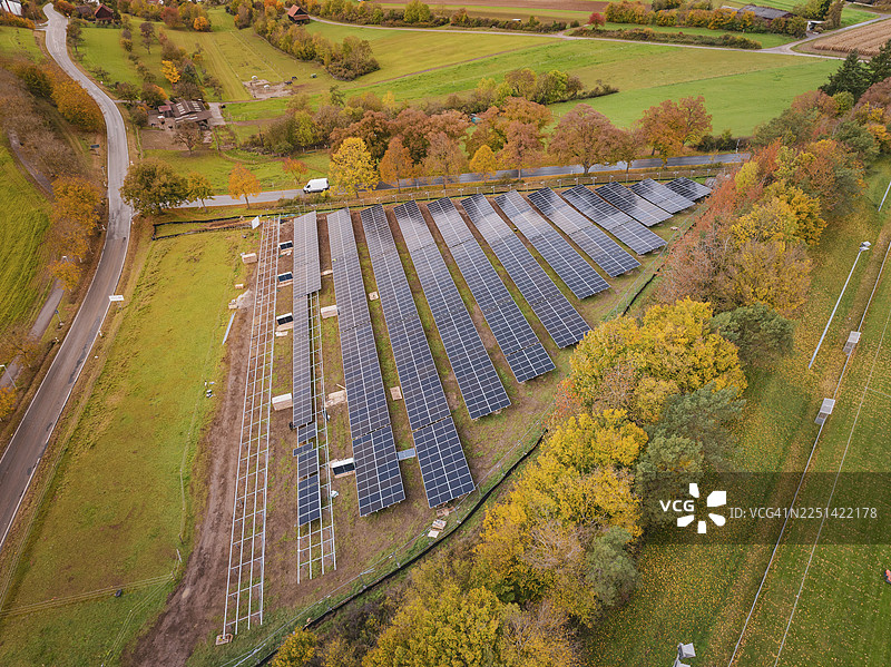 秋色中被树木环绕的太阳能电池板集合，位于德国威尔德施塔特的Bau PV Freifaechenanlage。图片素材