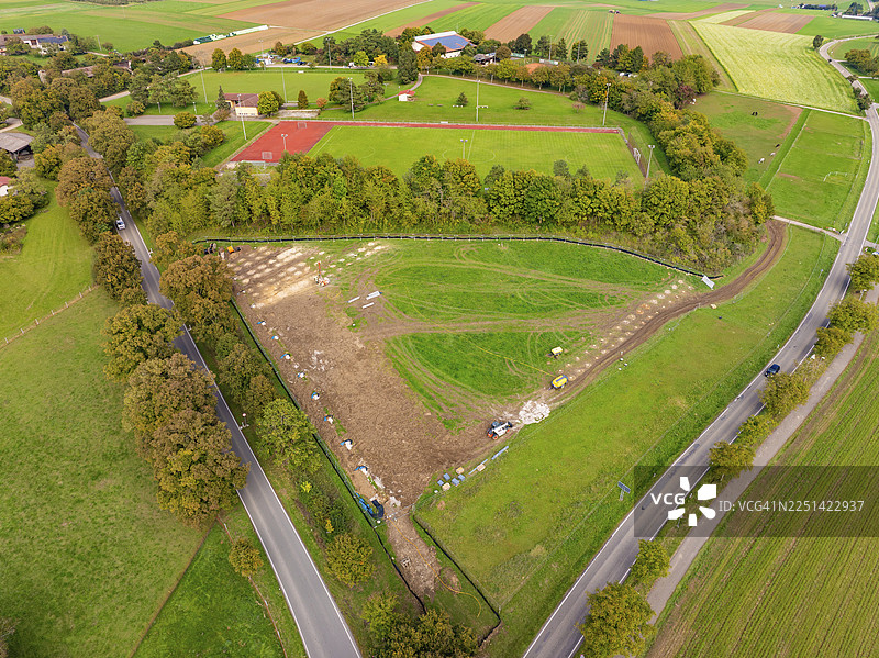 绿色的景观，有网球场和树木成荫的道路，天空多云，位于德国魏尔德施塔特的PV Freifaechenanlage建筑工地。图片素材