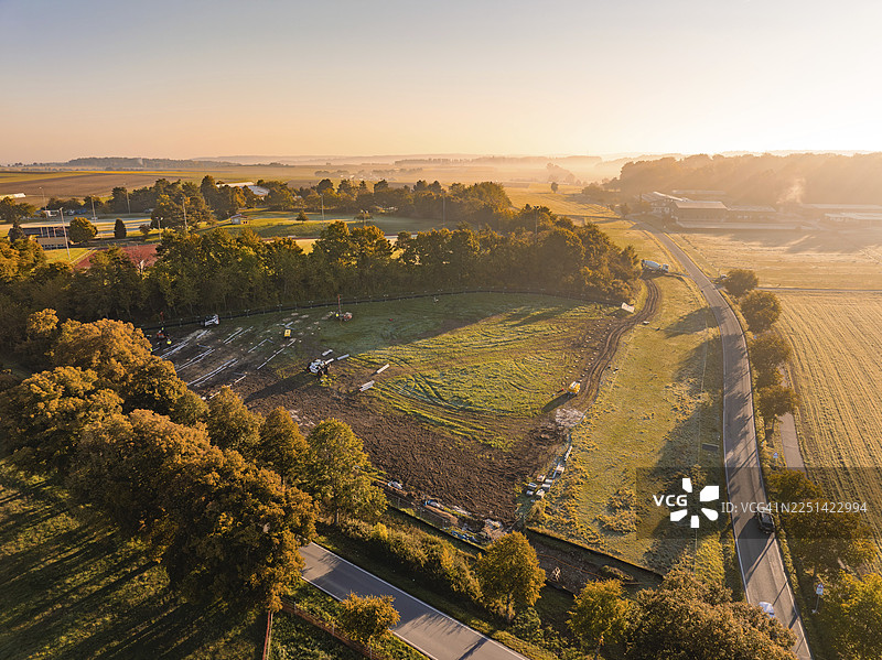 柔和的晨光照耀下的田野和树木，德国魏尔德施塔特Bau PV Freifaechenanlage光伏开放区图片素材