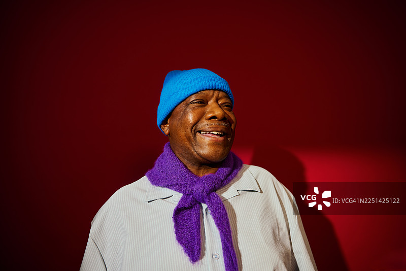 一位年长的男士戴着色彩鲜艳的针织帽和围巾，脸上带着微笑图片素材