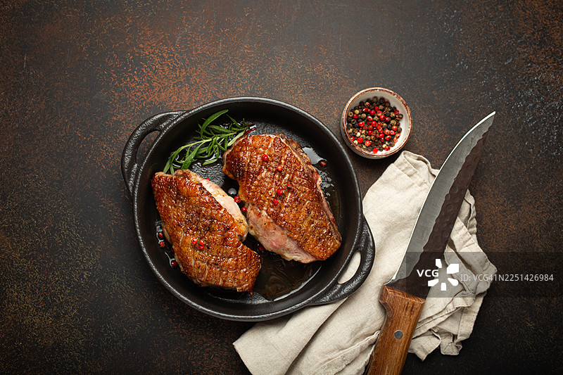 美味的烤鸭胸肉，配有迷迭香和彩椒，装在铸铁锅中，即刻可享用图片素材