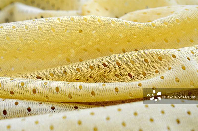 充满活力的黄色穿孔织物的特写，表面有纹理且透气图片素材