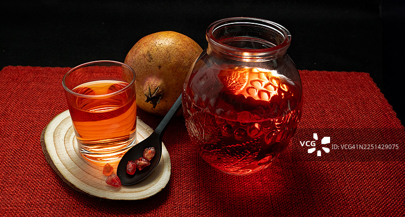 鲜红的石榴汁和石榴籽铺在红色的桌布上图片素材