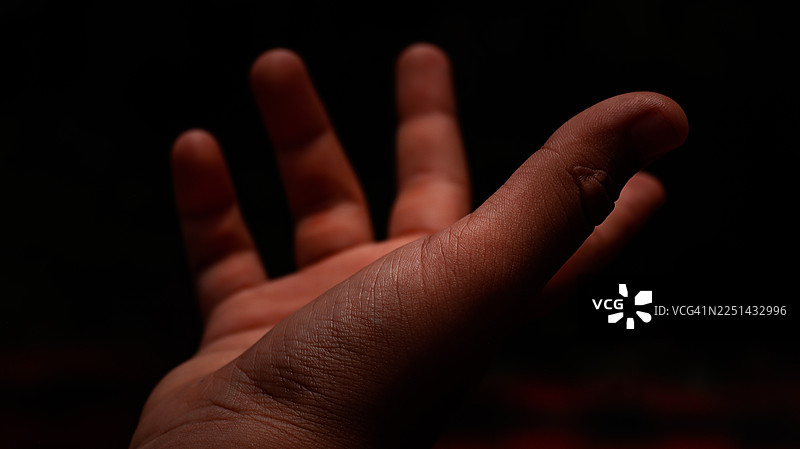 手部特写伸出，背景为深色，展示了纹理和细节图片素材