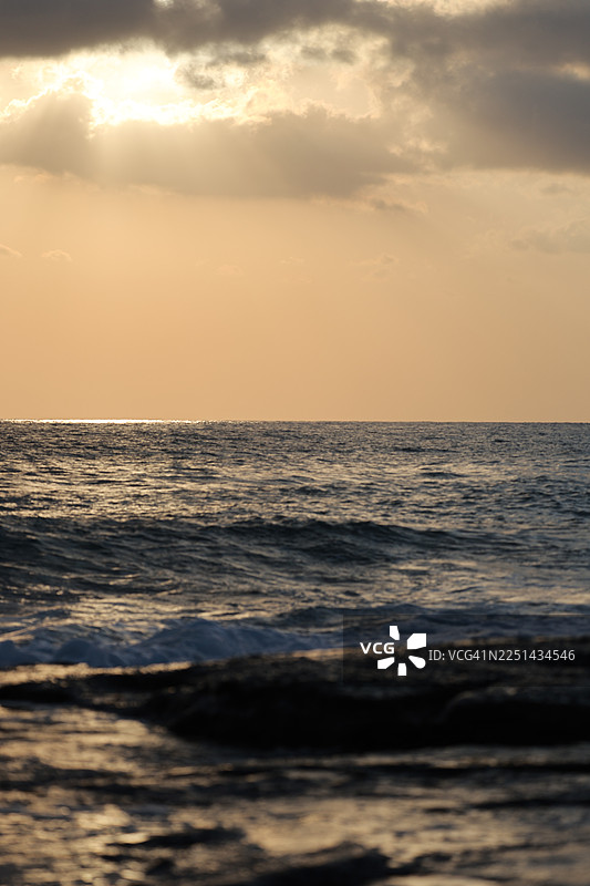 日落时分，海景与戏剧性的天空交相辉映，海浪拍打着海岸图片素材