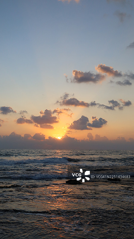 色彩鲜艳的日落映照在海面和云彩上，呈现出戏剧性的景象。图片素材