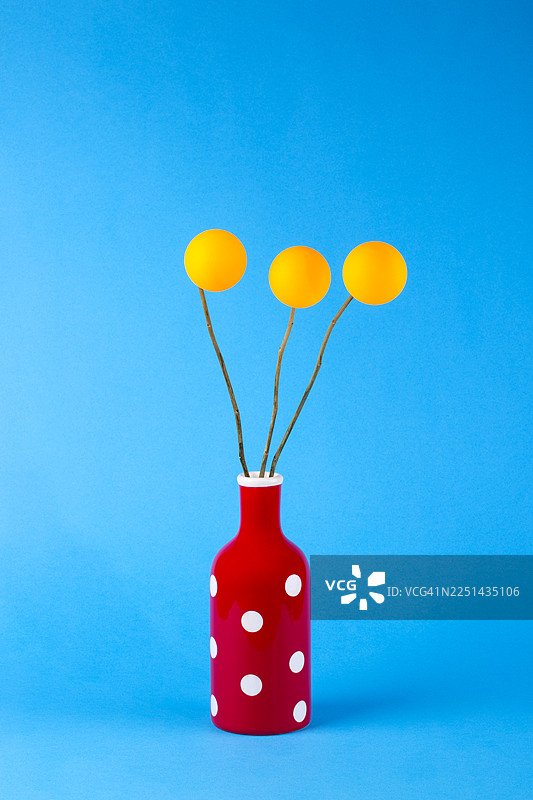 鲜艳的红色波点花瓶，带有黄色装饰元素，背景为亮蓝色图片素材