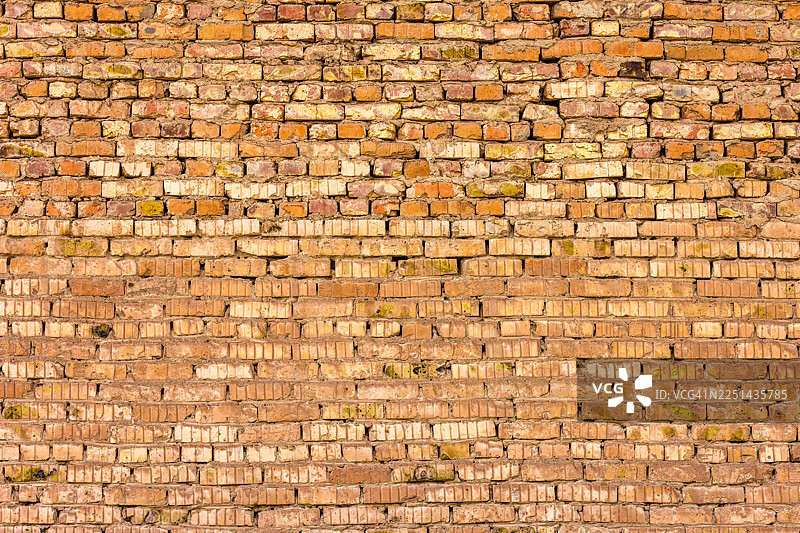 一张老旧、饱经风霜的砖墙的帧全景拍摄，砖块呈现出深浅不一的红色和黄色，展现了其纹理和风化痕迹图片素材