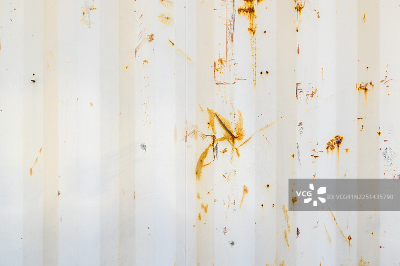 一张老旧的白色波纹金属墙的特写，上面有铁锈图案，形成抽象纹理背景图片素材