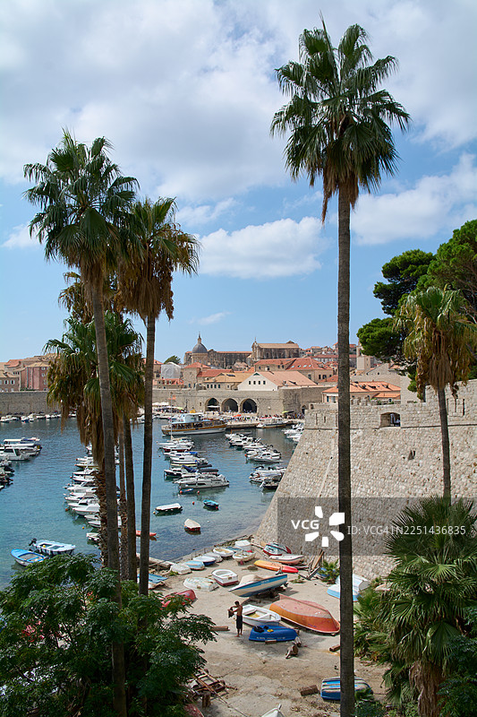 俯瞰克罗地亚杜布罗夫尼克海边的棕榈树、天空、船只和历史建筑图片素材