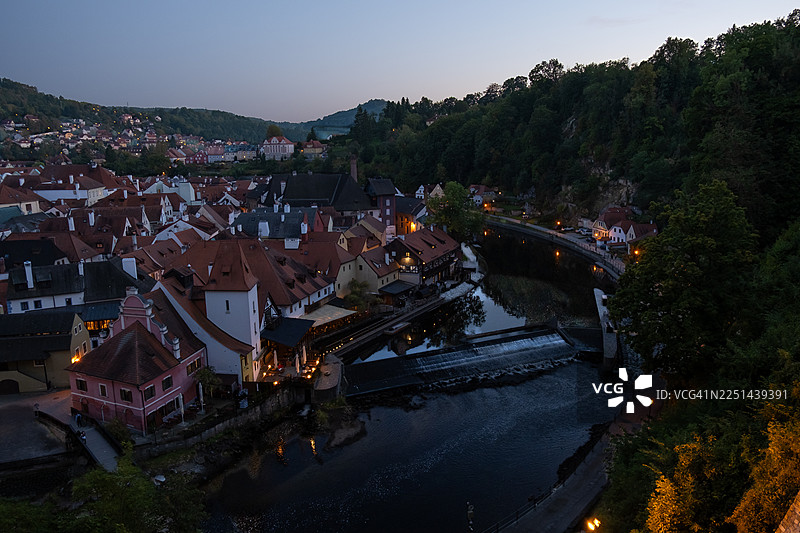 夜幕降临，温暖的灯光点亮了河畔的历史古镇，这是高角度的俯瞰视角。图片素材