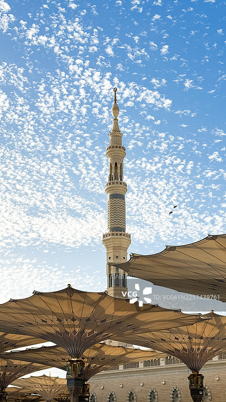 蓝天白云下，清真寺宣礼塔与巨大的伞图片素材