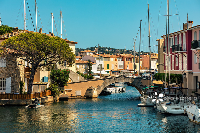 法国格里莫港，风景如画的运河，船只和色彩缤纷的房屋在晴朗的蓝天下图片素材