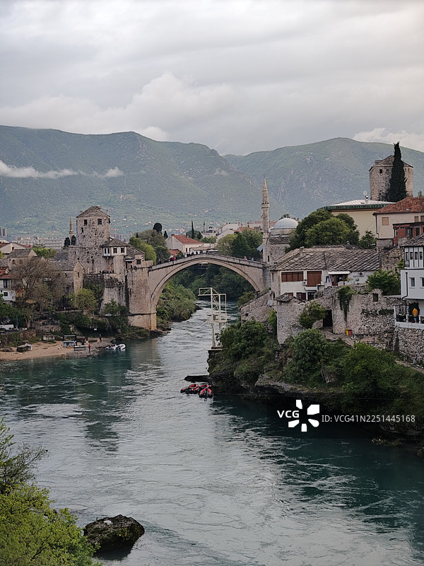 波斯尼亚和黑塞哥维那莫斯塔尔市的内雷特瓦河上的历史悠久的斯塔里莫斯桥，背景是群山和多云的天空图片素材