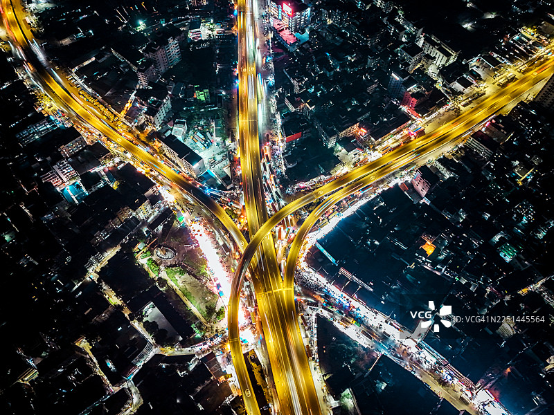 夜间充满活力的城市景观的鸟瞰图，展示了灯火辉煌的建筑以及复杂的公路和道路网络图片素材