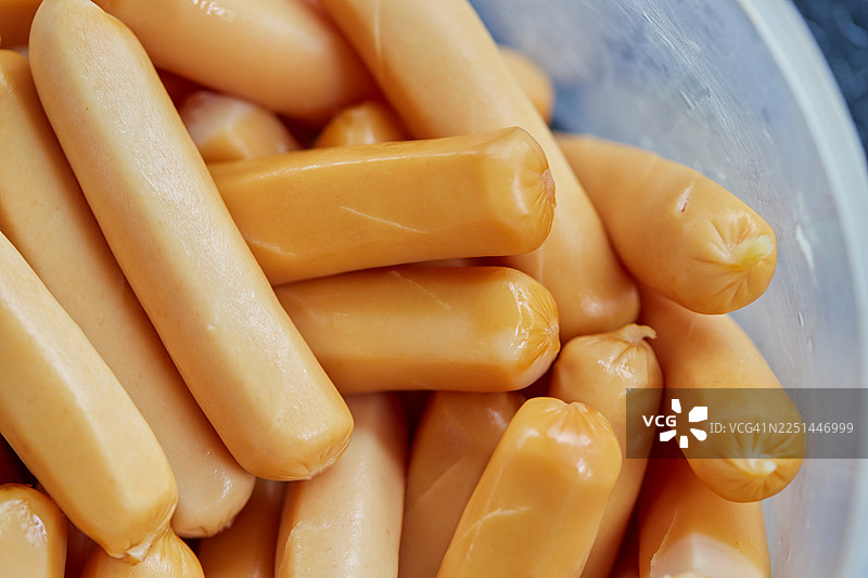 一个塑料容器中许多生香肠的特写全景镜头，可供烹饪或储存图片素材