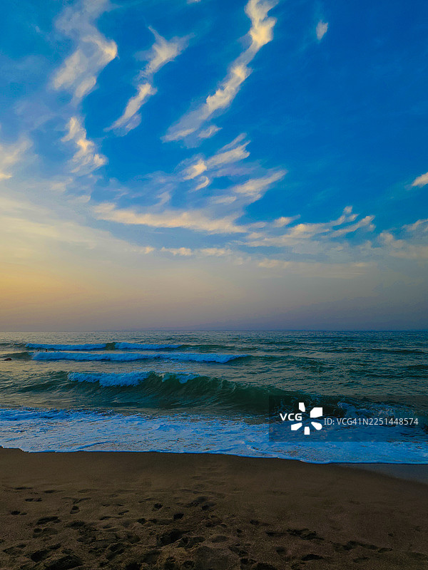 夕阳映照下，海浪拍打着沙滩图片素材
