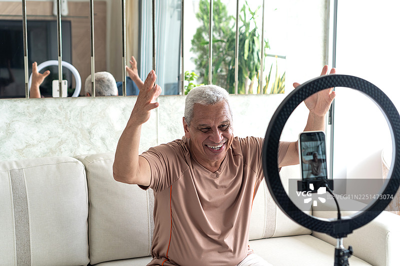 一位老年男子正使用环形灯在社交媒体上录制视频图片素材