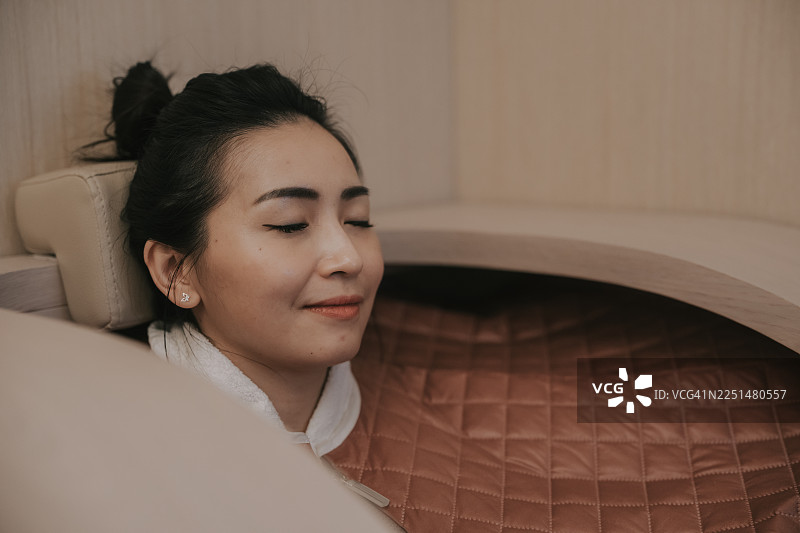 放松的亚洲女性在水疗中心享受健康胶囊护理图片素材