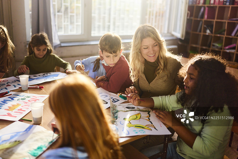快乐的老师在学校的美术课上指导她的学生。图片素材