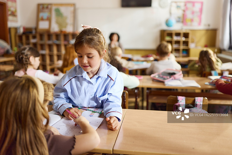 女学生在教室里帮助朋友上课。图片素材