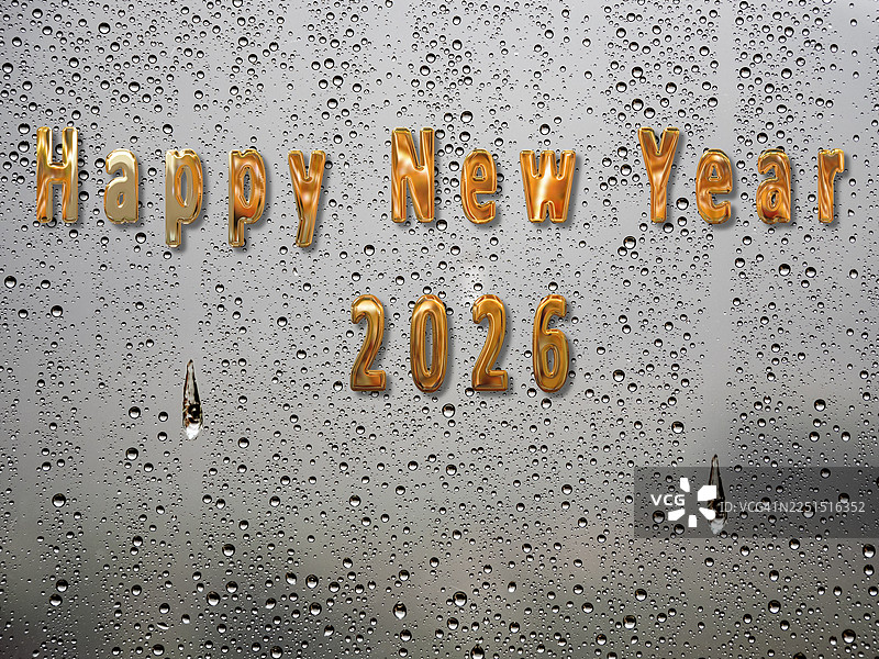 2026新年快乐，带有闪亮的金属金色字母，背景是滑落的雨滴。图片素材