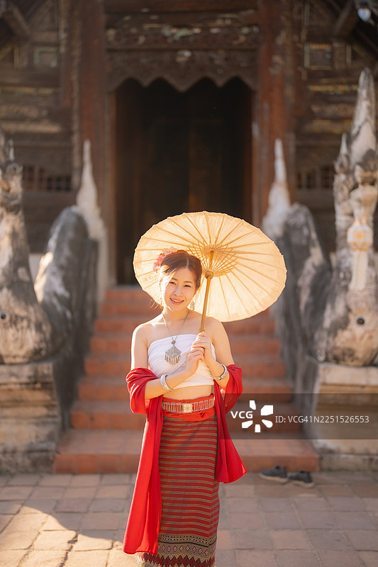 在泰国北部的清迈，年轻女子身着兰纳泰传统服饰在寺庙中游览。图片素材