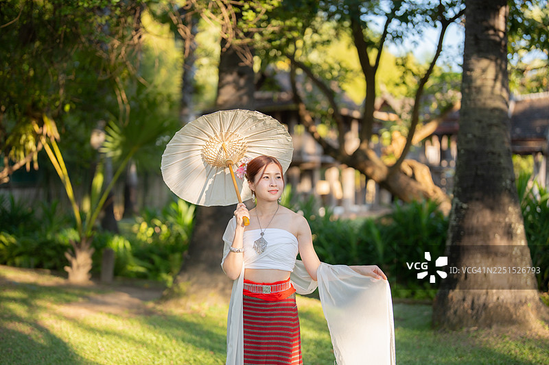 一位身着兰纳泰式传统服饰、放松的亚洲女性在清迈茵他瓦洛寺（Wat Intharawat）旅游图片素材