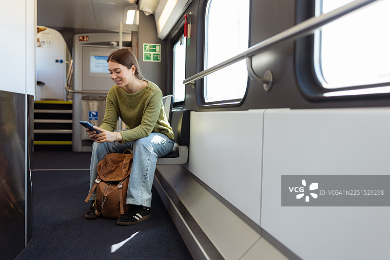 年轻女子坐在火车座位上使用手机图片素材