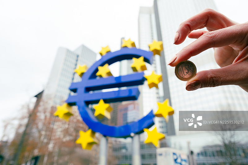 欧元的1欧元硬币在法兰克福的欧元符号前图片素材