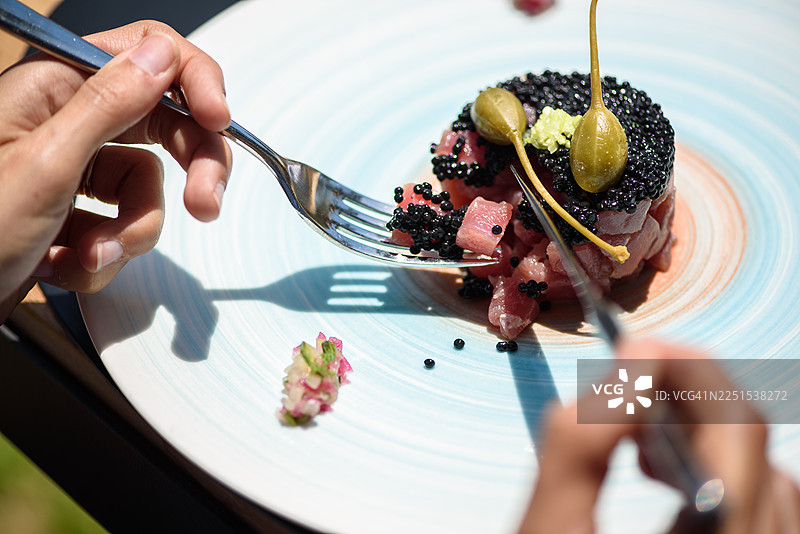 一个人正在吃金枪鱼塔塔，配鱼子酱和水瓜柳图片素材