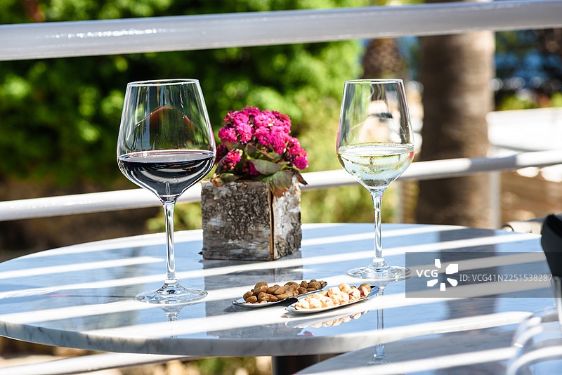 户外露台桌上的红白葡萄酒杯配坚果图片素材