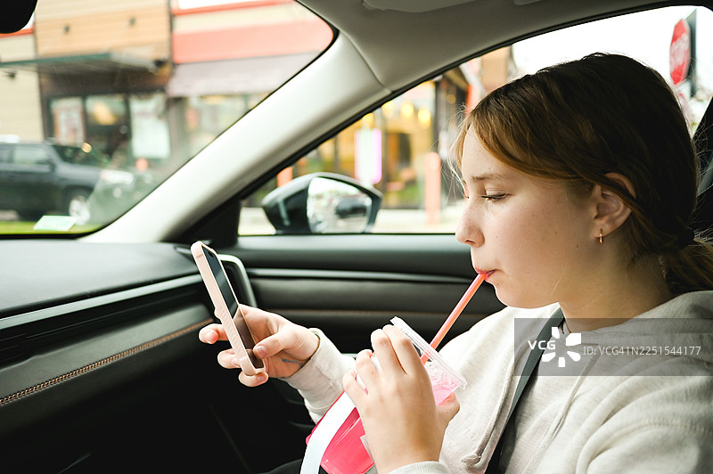 青少年在车里玩手机并喝酒图片素材