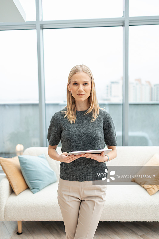年轻的女商人在现代办公室里拿着数字平板电脑图片素材
