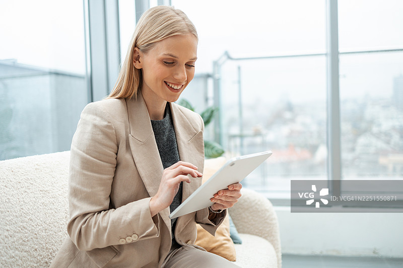 优雅的职业女性在办公室里微笑着使用数码平板电脑图片素材