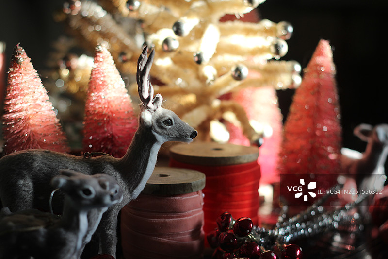 复古风格的瓶刷圣诞树装饰房间以迎接节日。包括驯鹿、天鹅绒丝带卷以及粉色装饰品。图片素材