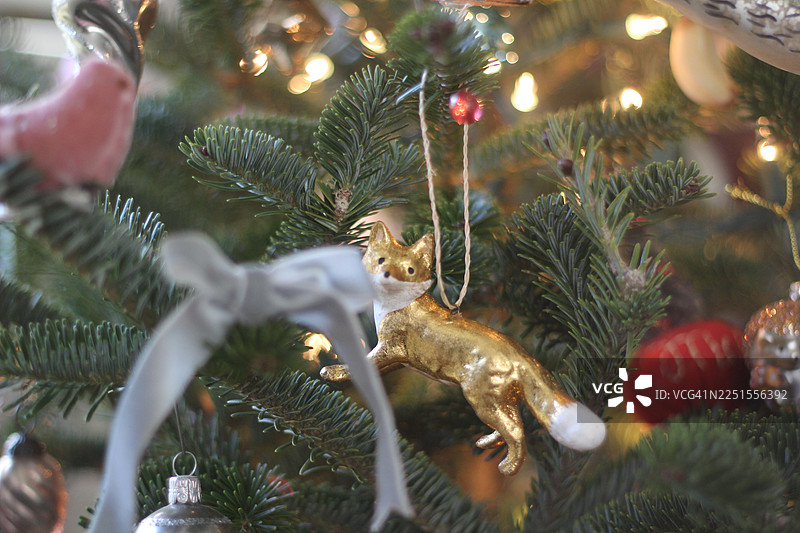 一套复古风格的装饰品。闪亮的圣诞饰品装饰着一棵新鲜的圣诞树。狐狸饰品。图片素材