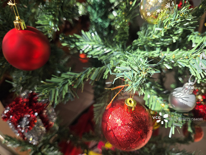 装饰精美的圣诞绿树，装饰有金色礼盒和叶子，背景虚化。装饰精美的圣诞树，背景虚化。图片素材