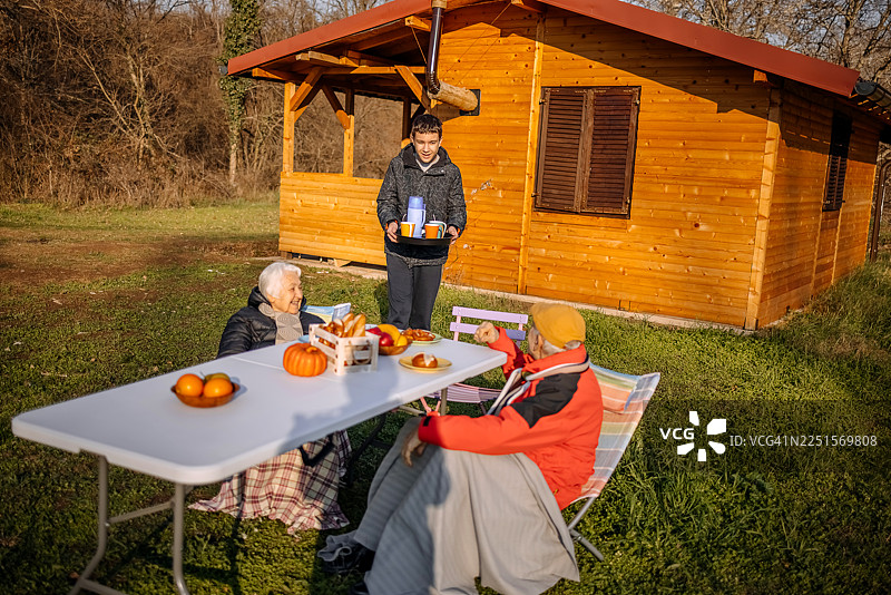 老人们在山间的小屋前一起度过时光，并享用热饮图片素材