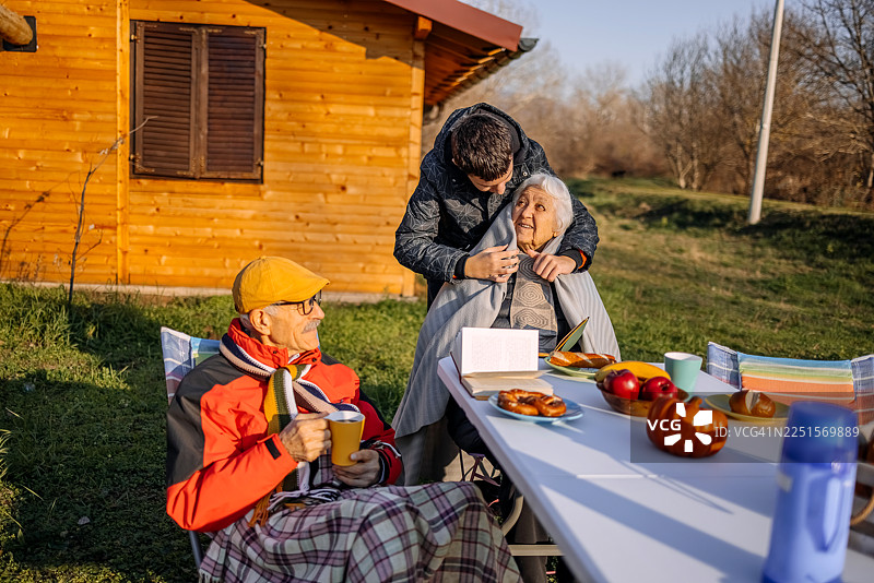 老人们在山上的小屋前共度时光，他们的孙子正在帮忙盖毯子图片素材