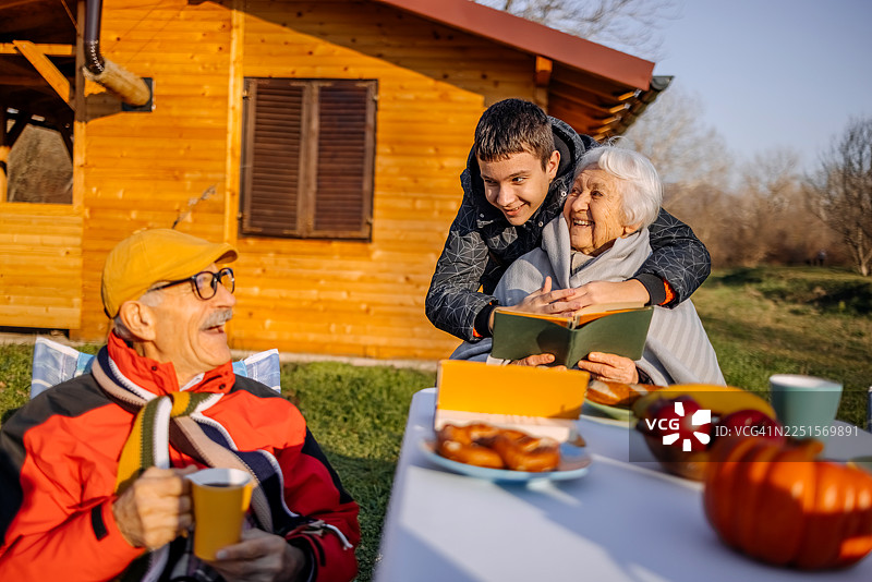老人们在山脚下的别墅前共度时光，他们的孙子正在帮忙盖上毯子图片素材