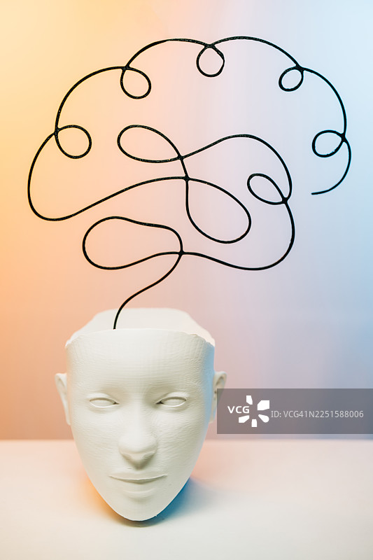 一张白色的面具摆放在平面上，上方悬浮着一个抽象大脑形状的黑色弧线。图片素材