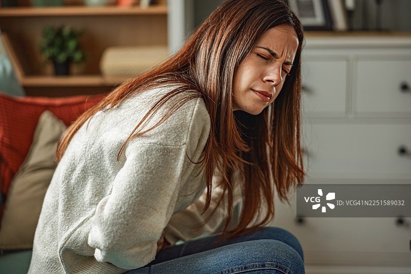 年轻女子在家中胃痛腹部疼痛图片素材