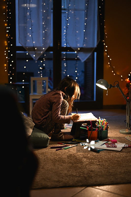 小女孩在夜晚画画，周围有很多小彩灯图片素材