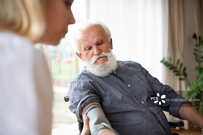 居家护士使用血压计测量血压。图片素材