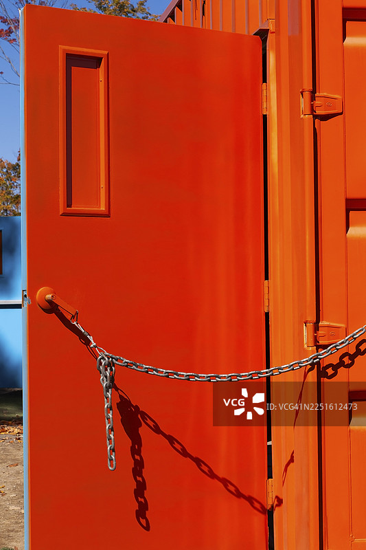 加拿大的魁北克省，一个明亮的荧光橙色金属盒形集装箱，门被链条拴着敞开图片素材