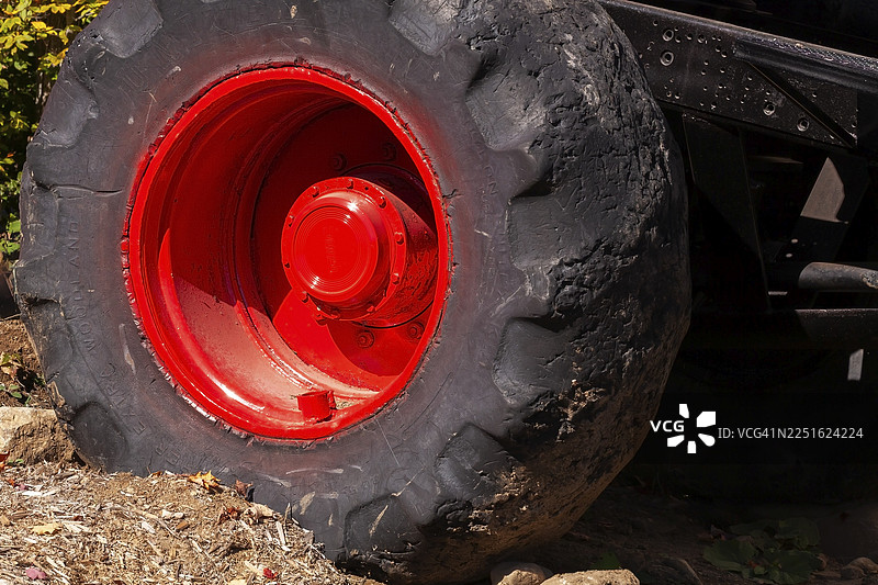 特写镜头，展示了安装在加拿大魁北克省的怪物卡车车辆的红色轮辋上的大型重型黑色橡胶轮胎的后侧视图。图片素材