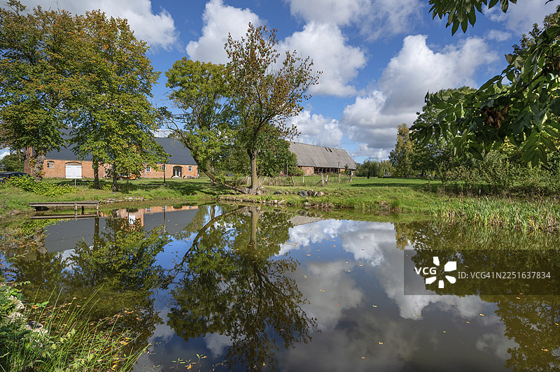 1923年,梅克伦堡-前波美拉尼亚州奥滕斯多夫庄园的马厩和谷仓,旁边有一个池塘图片素材