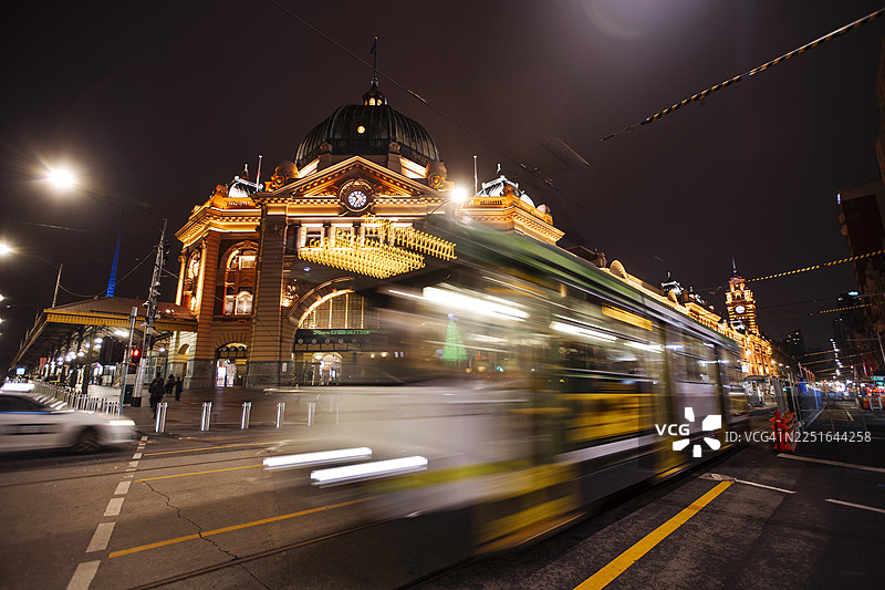 夜间有轨电车飞驰经过历史悠久的城市火车站图片素材